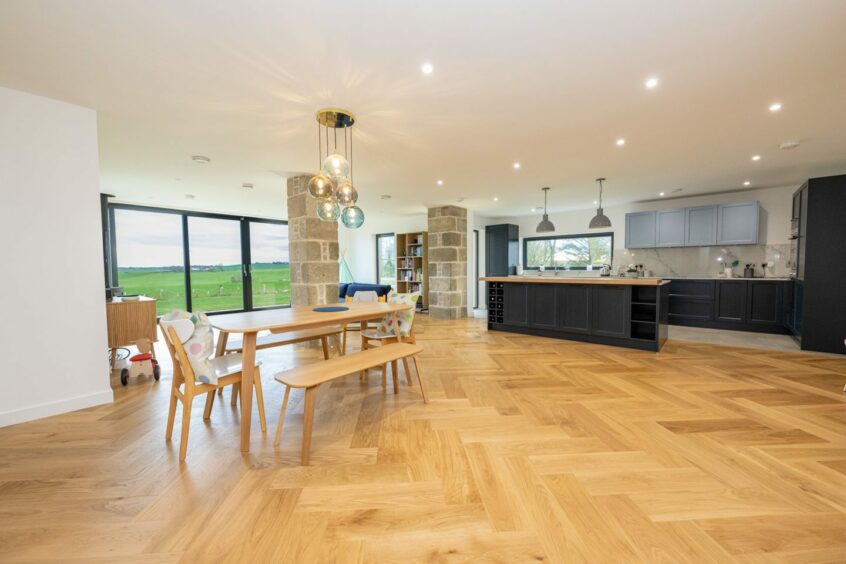 The open plan kitchen and dining areas of the Udny house, there's a living area at the far side of the room, with large glass patio doors looking out onto the Aberdeenshire countryside