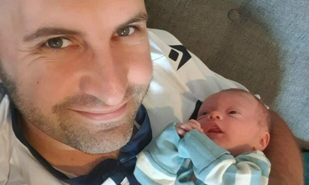 David Mackay looking at camera while holding baby Isla.