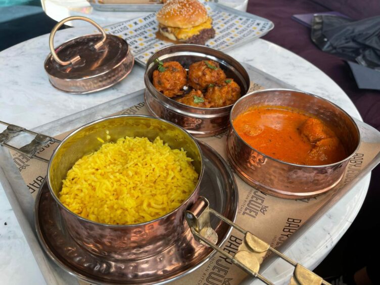 three metal tins, one with rice, another with curry and another with pakoras