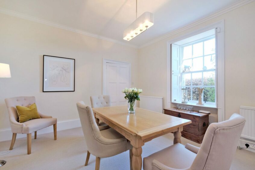 A room of Eden Cottage near Inverurie featuring a pale wooden table, cream walls and carpets and plush cream chairs