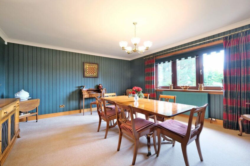 The spacious dining room with seating for 6, green striped wallpaper and red and green curtains