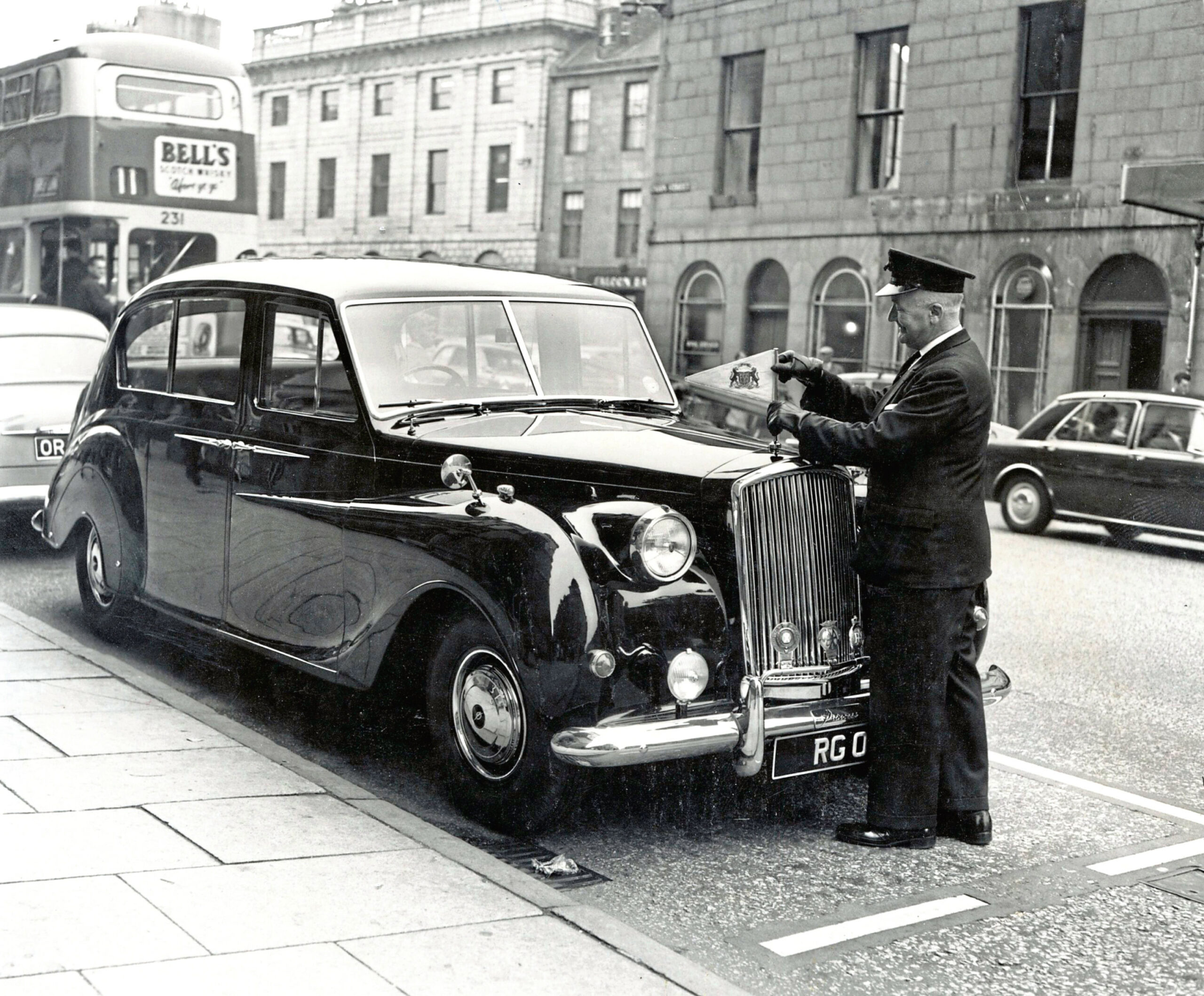 The uniformed driver adjusts the pennant on the lord provost’s car, an Austin Vanden Plas Princess, parked outside the Town House in Union Street, Aberdeen, in August 1964.