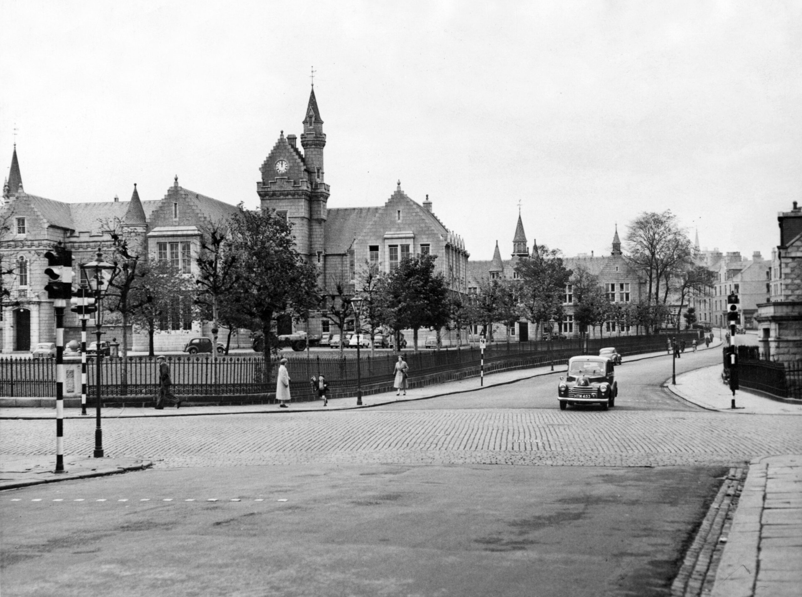 A cobbled Skene Street runs across the junction of Esslemont Avenue and Rose Street, in Aberdeen, with the imposing Grammar School building dominating the skyline in October 1958.
