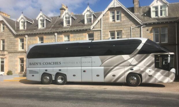 Side-on view of Bain's Coaches bus outside hotel.