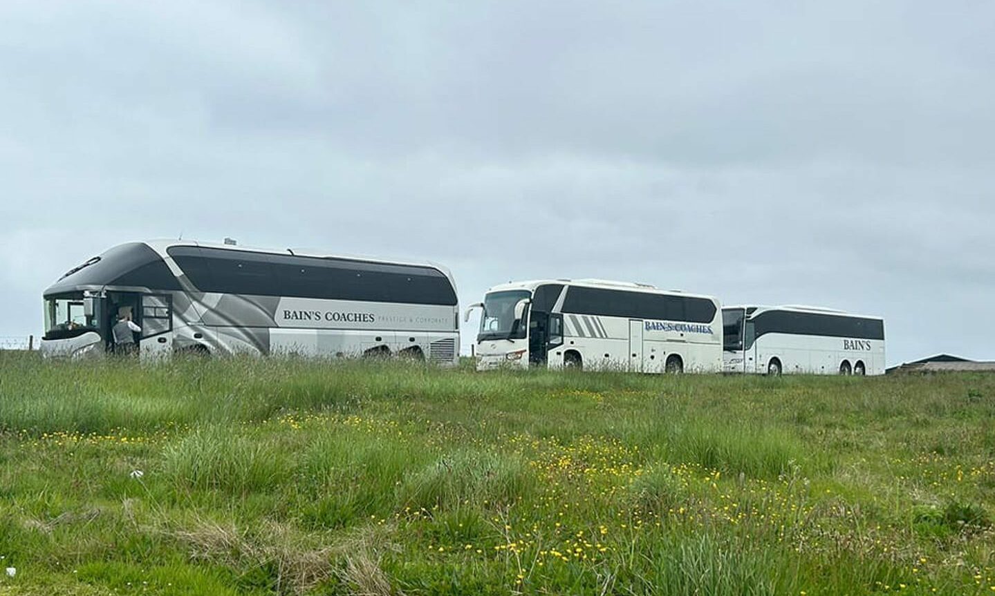 Three Bain's Coaches coaches in a line in the countryside. 