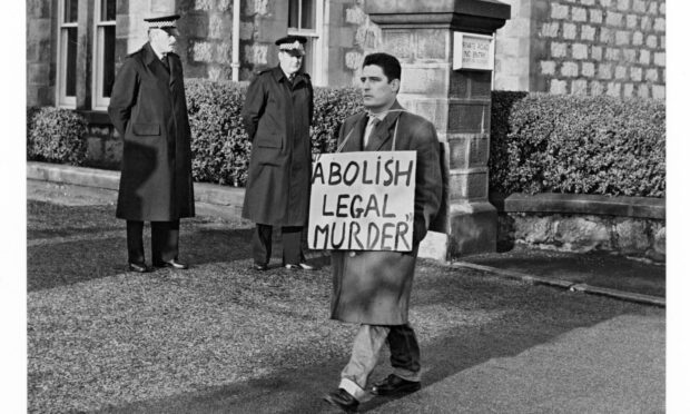 Two policemen on guard outside Craiginches Prison on the morning of the execution while placard-bearing protestor John Gibson demands the abolition of hanging. Image: DC Thomson