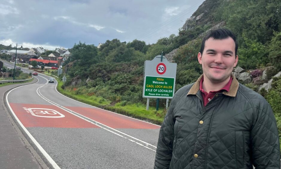 Councillor Ruraidh Stewart with the new 20mph sign at Kyle of Lochalsh behind.