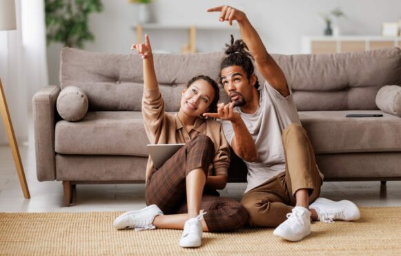 Young couple sitting on floor with digital tablet, discussing home project and builders' merchants in Aberdeen