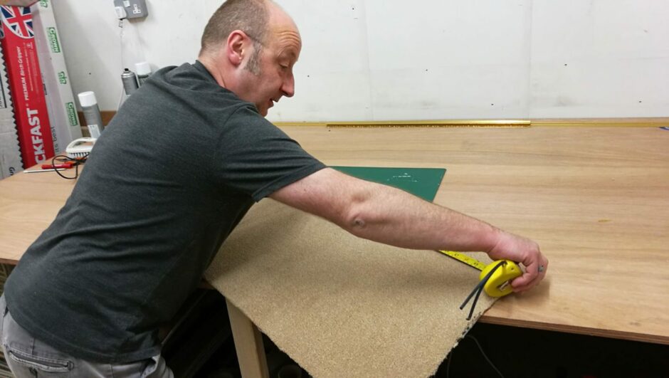 man meticulously measures a piece of carpet to fit in a home