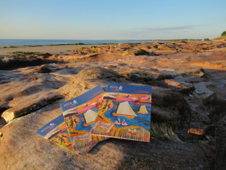 Booklets for Nairn Book and Arts Festival resting on a rock at Nairn Beach.