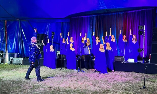 Members of the Highland Voices choir performing in a tent at Belladrum, who may be playing Edinburgh Fringe