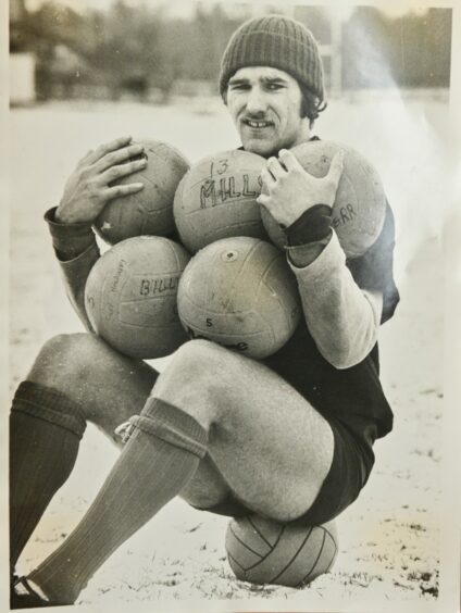 Billy MacDonald in his gear sitting on a ball, with five balls in his arms and balancing on his knees