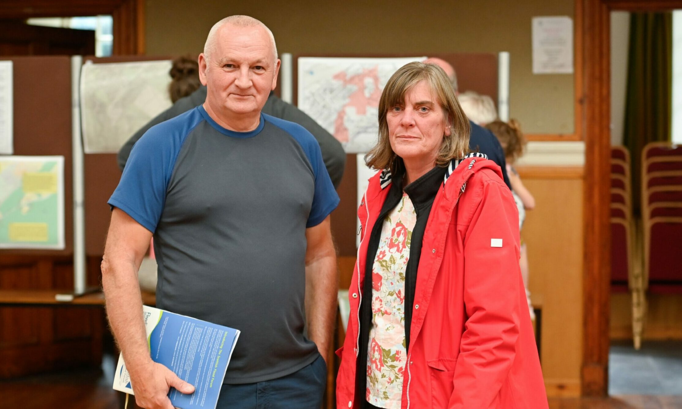 Willie Cameron and Pamela Winchester standing in the Fleming Hall in Aberlour with noticeboards behind. 