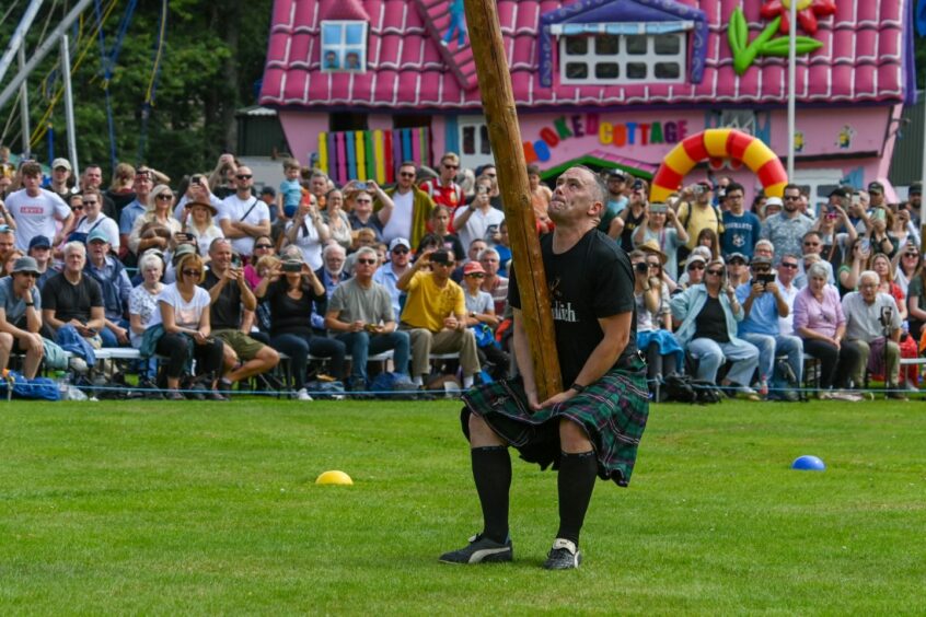 A man attempting the caber toss Ballater Highland Games 2023