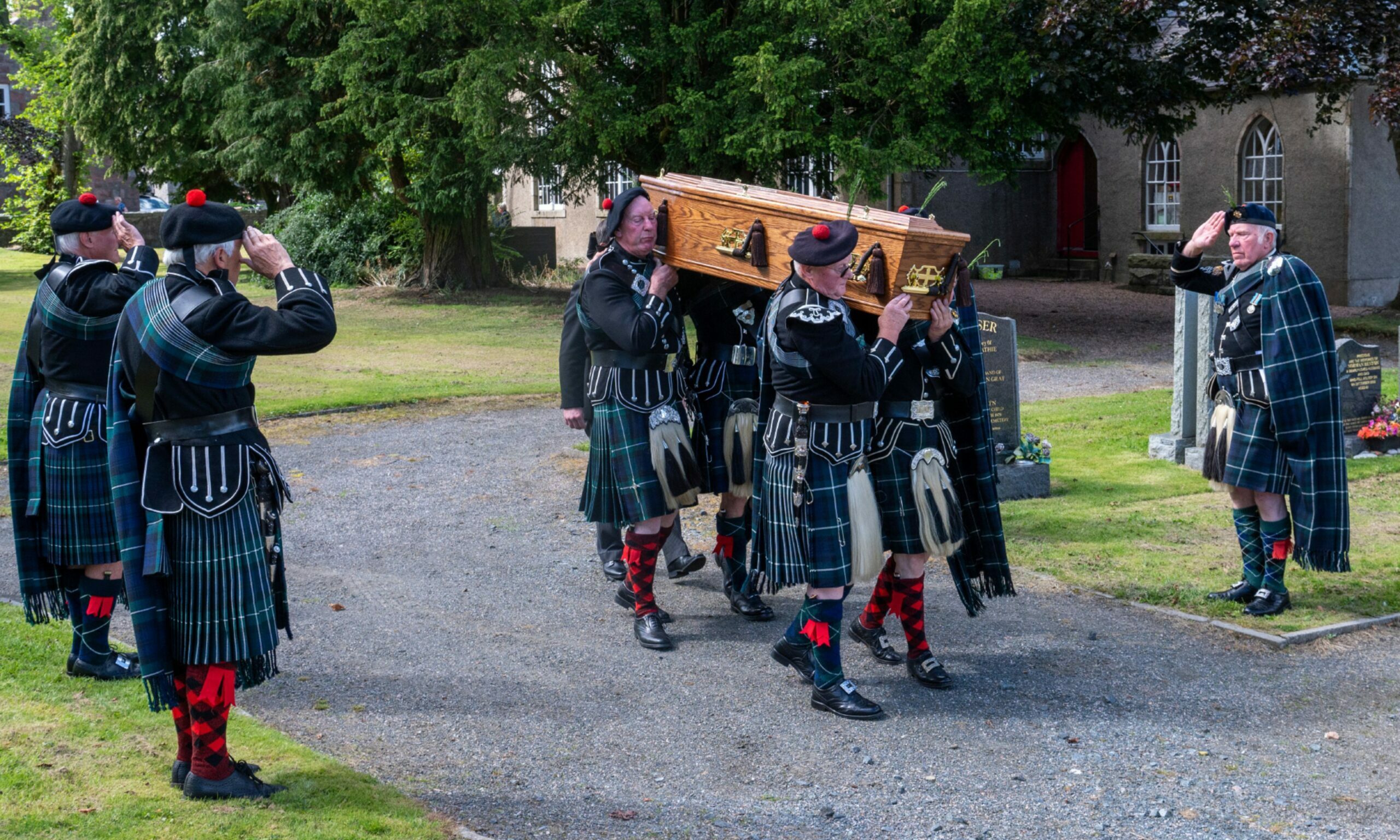 The Lonach Highlanders carry the coffin of Robbie Shepherd at his funeral