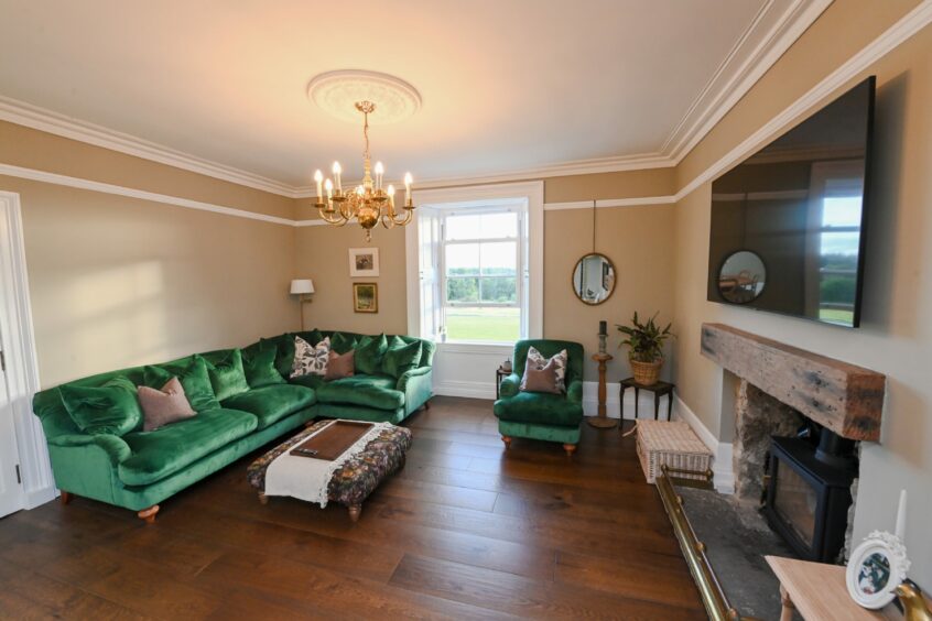 Stylish lounge within Cairnton Farmhouse featuring a large window with views of the Aberdeenshire countryside.