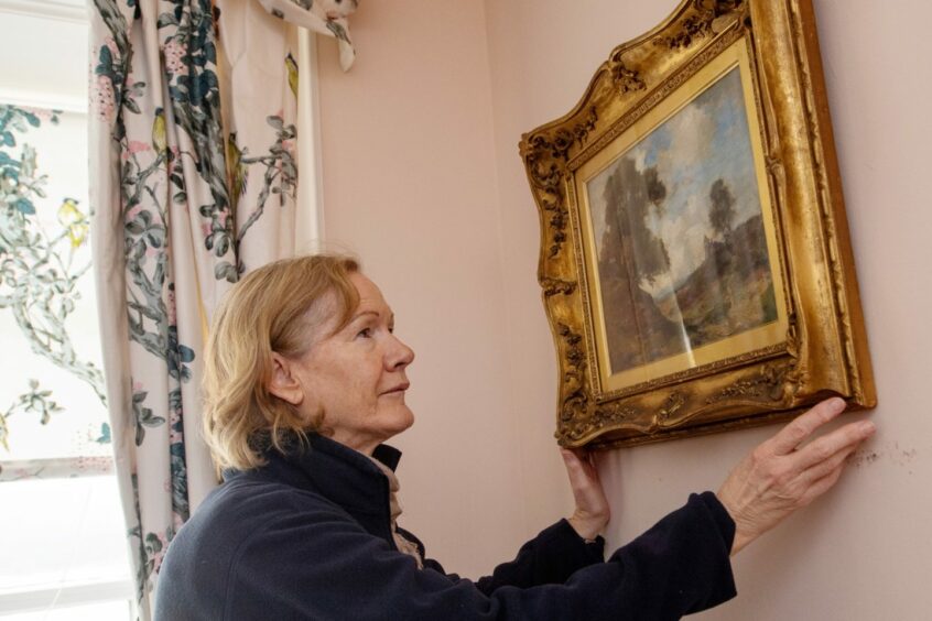 Volunteer Sheila Anderson adjusts a picture frame in the drawing room. 