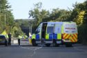 Police van and police officers, with cars on road.