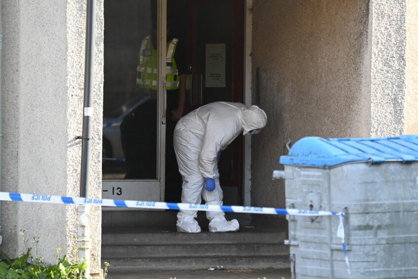 Forensic officer inspecting the entrance to the block of flats at Seaton Walk.