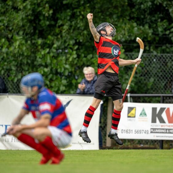 Lewis Cameron jumping in the air with his fist up during the Oban Camanachd  v Kingussie game