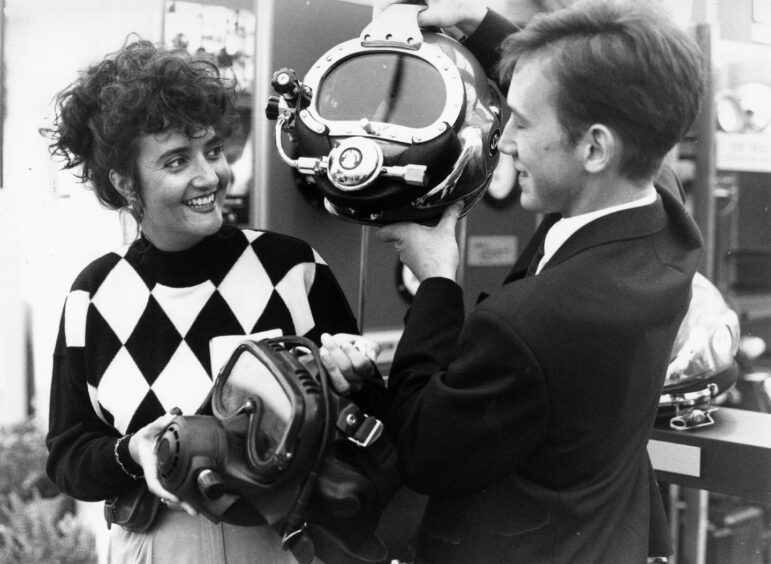 5 September 1991:
Corrine Jackson from Clarkson, Glasgow, is shown a selection of divers helmets by Graeme Clark of Subsea Services, George Street, Aberdeen, a leading manufacturer and distributor of diving equipment.

Used: EE 06/09/1991