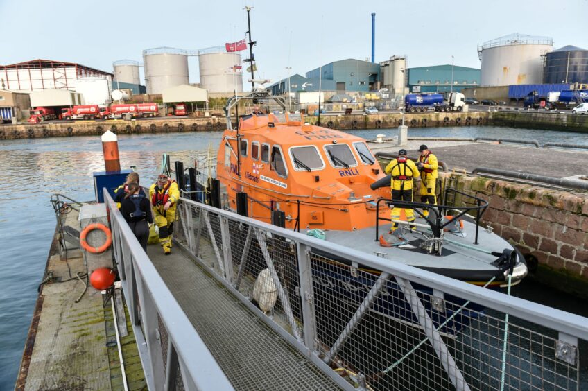 The lifeboat in harbour with crew busy on deck.