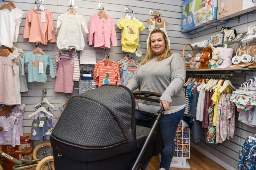 Gemma stands with a pram inside Daisy Tree Baby Boutique, Alford.