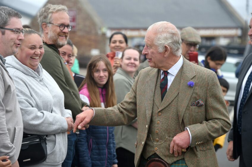 King Charles, dressed in his finest Highland dress, greets crowds of people.