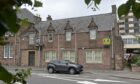 An old building in Inverness with a car parked in front of it.