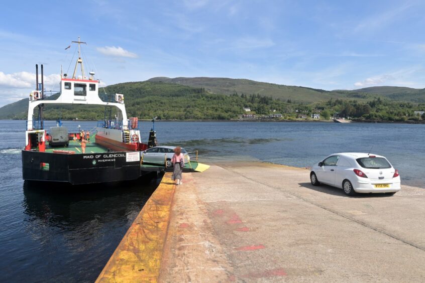 A white car drives down the ferry slip way towards Mv Maid of Glencoul as a grey car drives onboard.