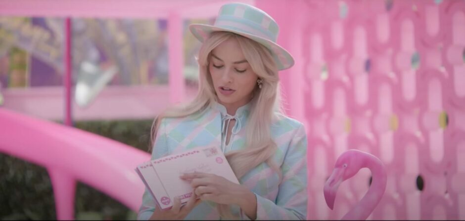 Margot Robbie as Barbie holding letters