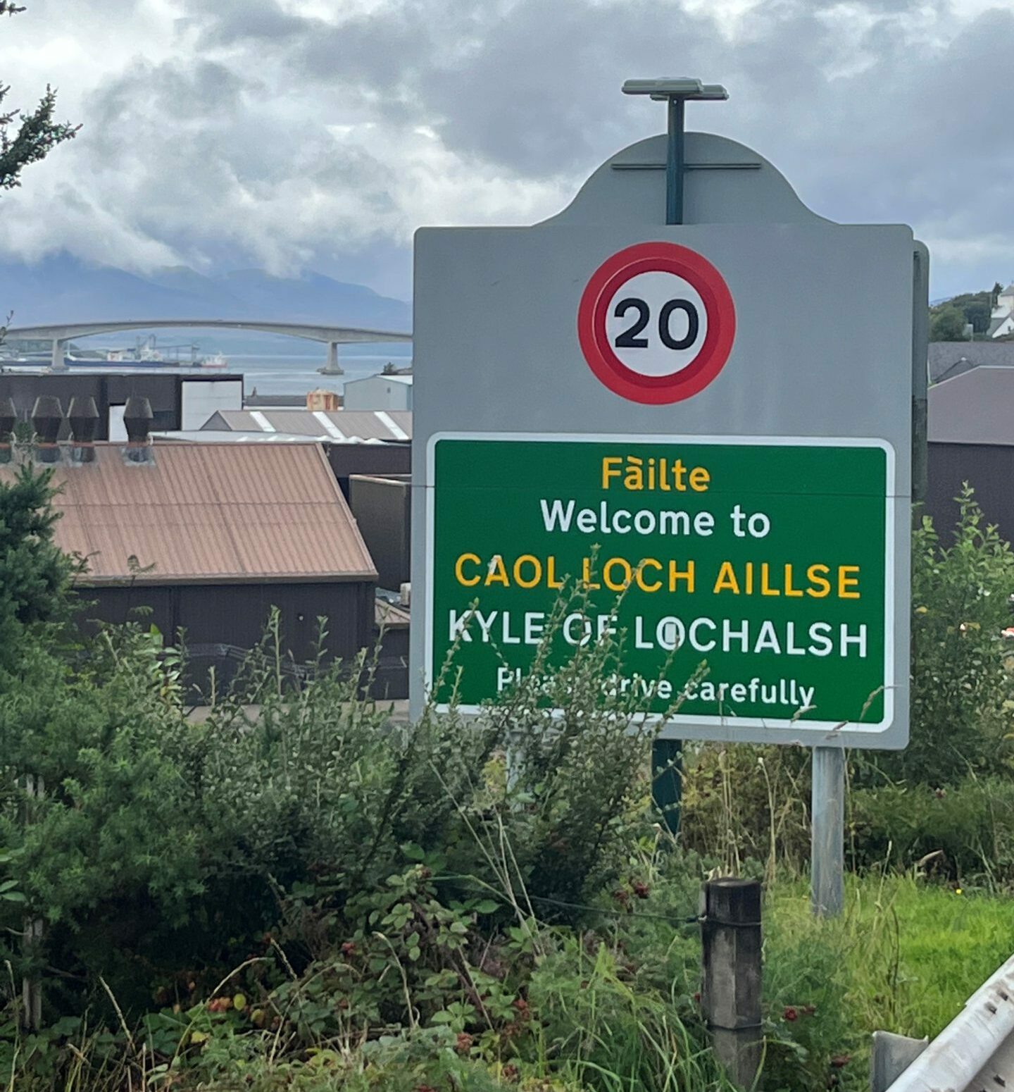 Close-up of 20mph sign at Kyle of Lochalsh with Skye bridge behind. 