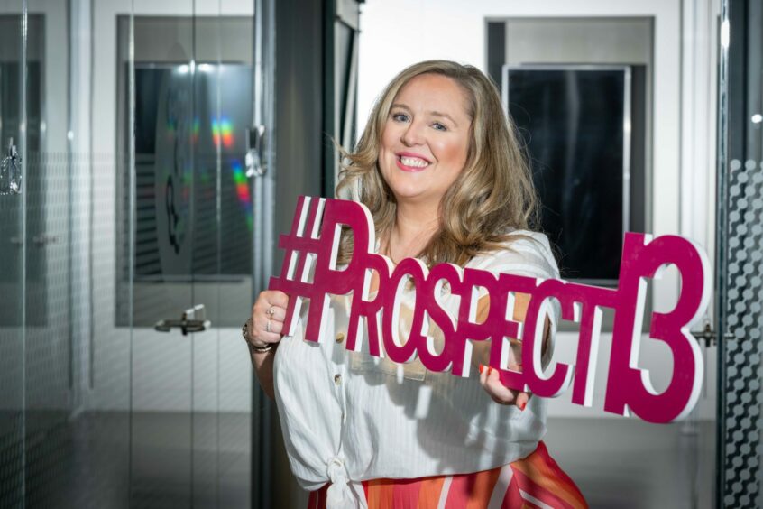 Cerri McDonald with a Prospect 13 sign. The firm is celebrating its fifth birthday. Image: Prospect 13.