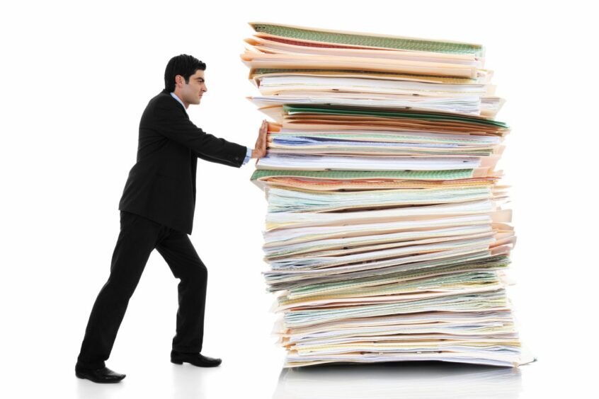Businessman pushing a giant stack of documents.