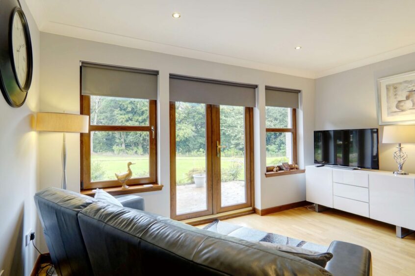 A living area with two windows and glass patio doors leading out to the garden.