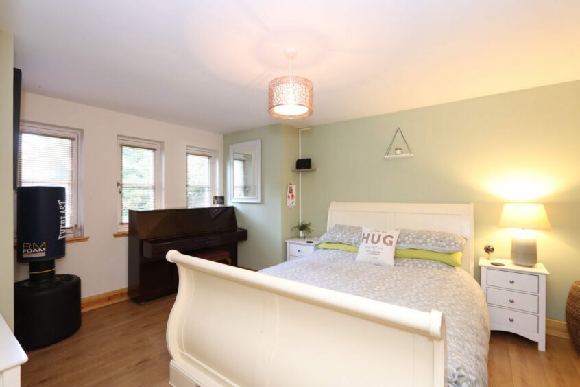 A bedroom with a lighter colour scheme, featuring pale green walls and pillows on the double bed