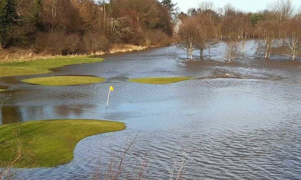 Close-up image of golf hole with surrounding course flooded. 