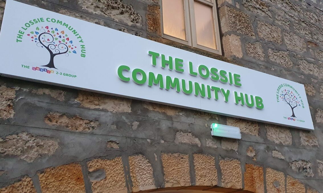 Sign saying "The Lossie Community Hub" in green letters above arched door. 