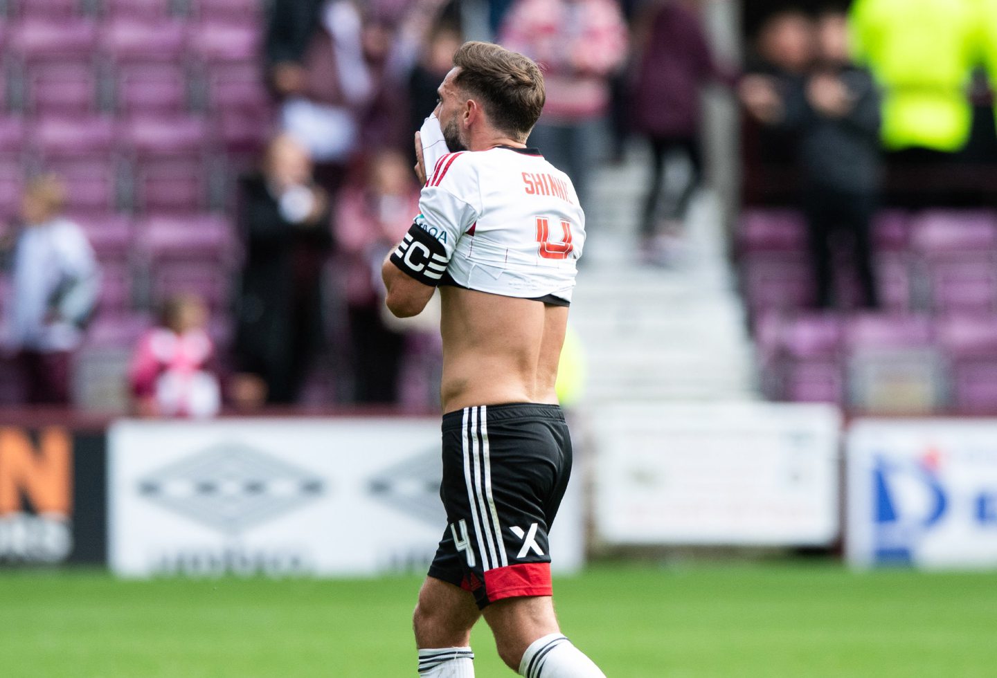 Aberdeen's Graeme Shinnie wiping his face with the hem of his shirt on the pitch