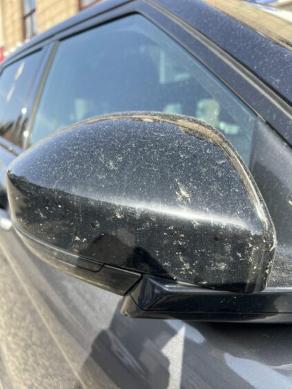 Rear view mirror of car covered in sand after a Saharan dust cloud hit Aberdeen.