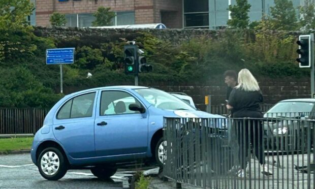 Crashed Nissan Micra, with two people standing.