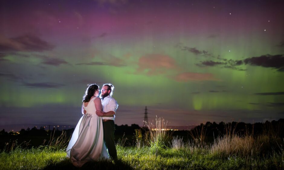 Bride and groom standing under the Northern Lights.