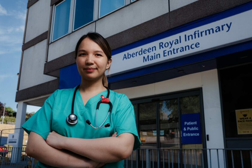 Junior doctor standing outside main entrance to Aberdeen Royal Infirmary.