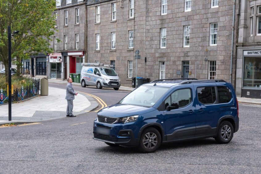 A blue Renault turning right at the junction. 