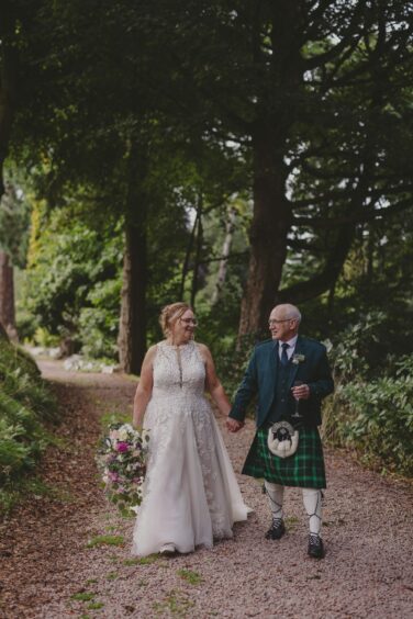 Sharon Travers and Martin Kelly walking hand in hand on their wedding day