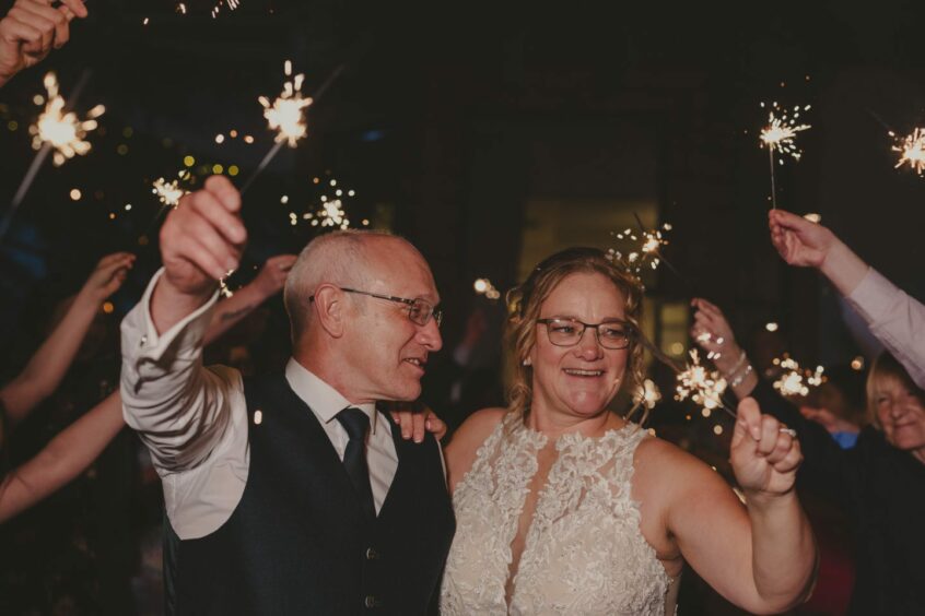 Sharon Travers and Martin Kelly holding sparklers at their wedding 