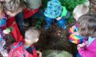 Children in a circle looking down at something together.