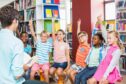 Kids raising their hands in library at school