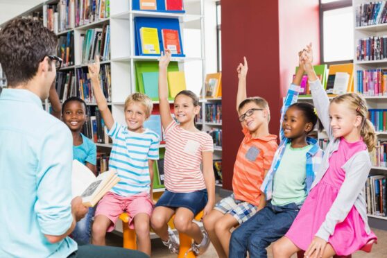 Kids raising their hands in library at school