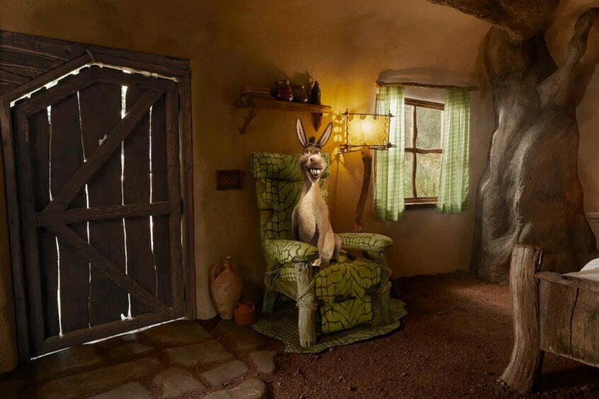Donkey sitting on a chair in Shrek's swamp, for rent on Airbnb.